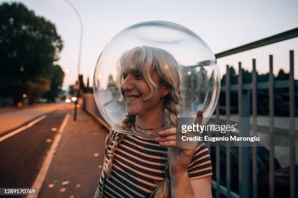 young woman on street with glass bowl on her head - astronaut helmet stock-fotos und bilder