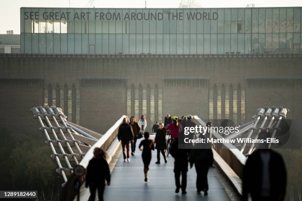People walking over Millennium Bridge at sunset, with Tate Modern Gallery in London, England, UK, Europe.