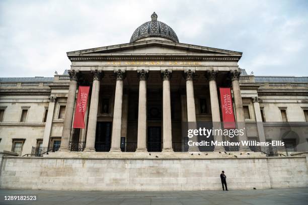 Quiet and empty Central London in Covid-19 Coronavirus lockdown with one person walking at The National Gallery at Trafalgar Square, a popular...