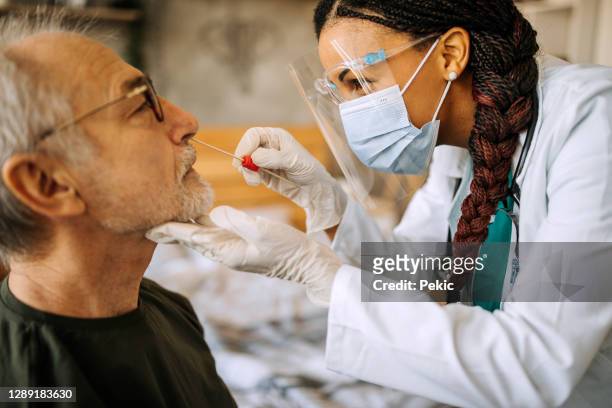 médico en una visita a casa a un hombre de la tercera edad - coronavirus fotografías e imágenes de stock