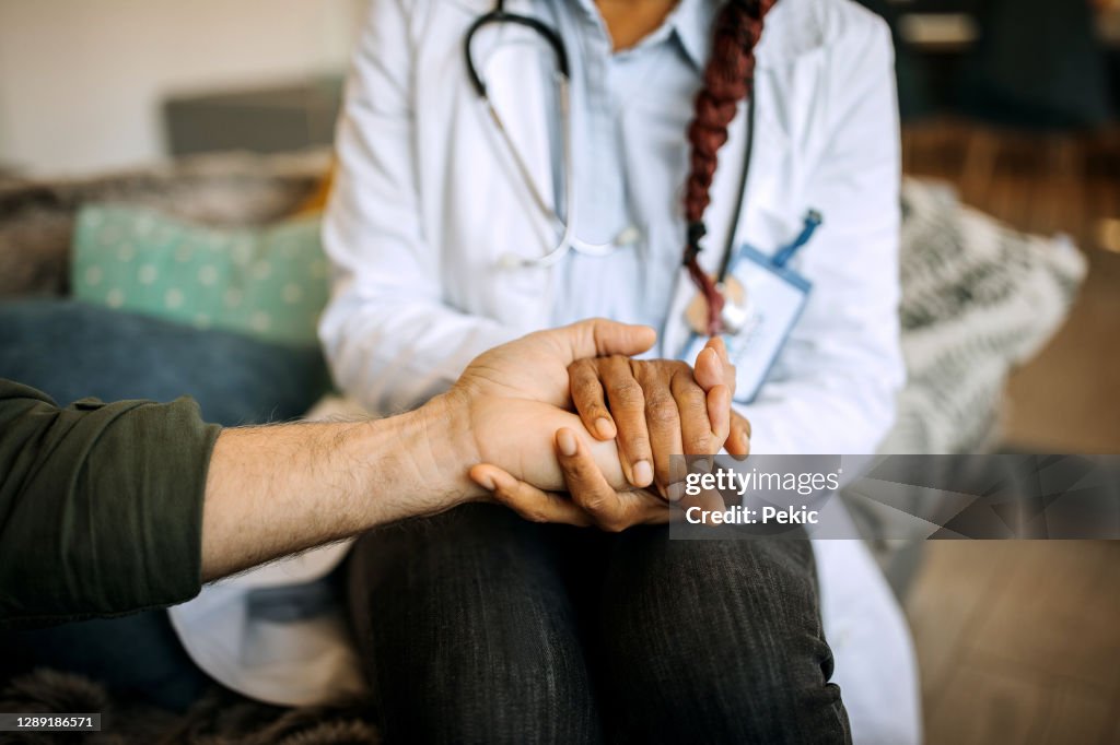 Doctor comforting patient at patient's home