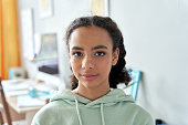 African american teen girl high school student looking at camera at home. Generation z mixed race pretty teenager standing in bedroom casual interior, headshot close up front portrait.