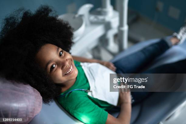 ritratto di una ragazza carina seduta sulla sedia del dentista - dentista bambini foto e immagini stock