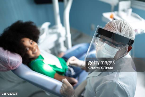 portrait of a mature dentist with child patient - face shield stock pictures, royalty-free photos & images