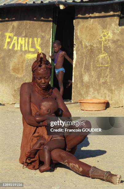 Femme Himba portant son enfant dans un village Pourros le 12 juin 2004, Namibie