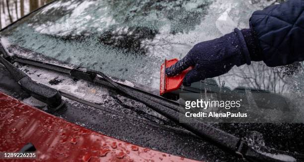 hand close up het schoonmaken van het ijs van de voorruit van de besneeuwde auto - ruitenwisser stockfoto's en -beelden