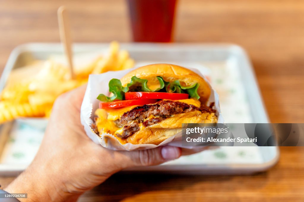 Man holding cheeseburger, close-up personal perspective view