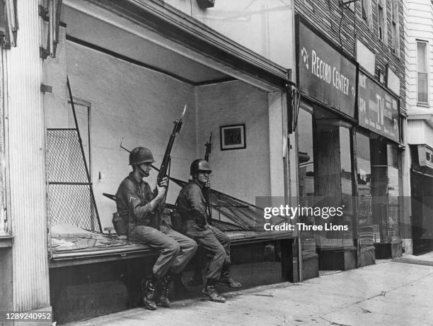 Soldiers sitting in the window of a looted store after a night of rioting in Detroit, Michigan, July 1967. Violence erupted after a police raid on an...