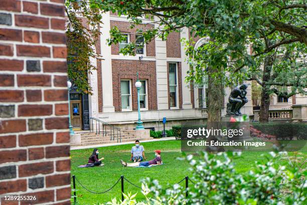 Three Students with Protective Masks sitting on lawn in front of Philosophy Hall, Columbia University, New York City, New York, USA.