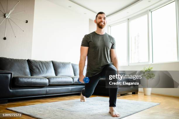 young sporty man having sports training with dumbbells at home - lunge imagens e fotografias de stock