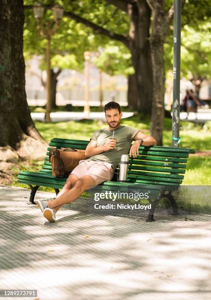 joven bebiendo té mate en un banco del parque en el verano - yerba mate fotografías e imágenes de stock