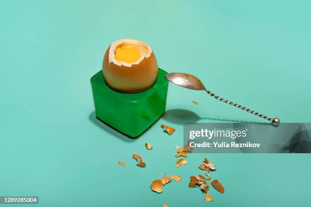 one soft-boiled golden egg with spoon in egg cup on the turquoise background - eierbecher stock-fotos und bilder