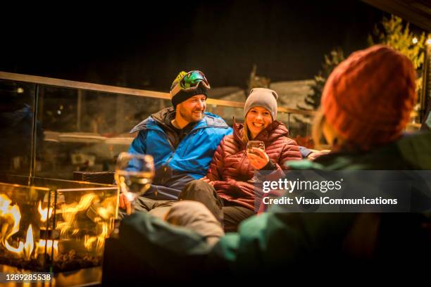 vrienden die door brand bij ski apres bij nacht zitten. - après ski stockfoto's en -beelden