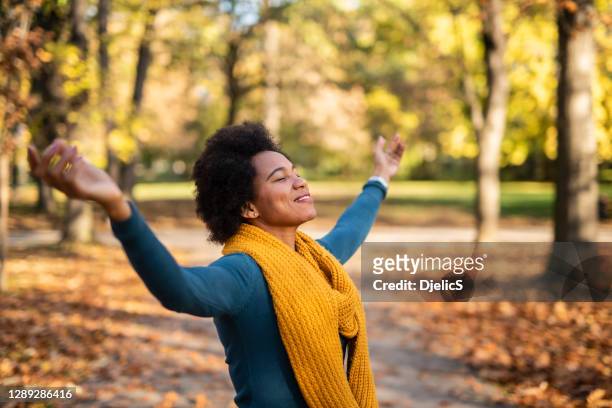 african american woman day dreaming in public park on beautiful autumn day. - black woman praying stock pictures, royalty-free photos & images