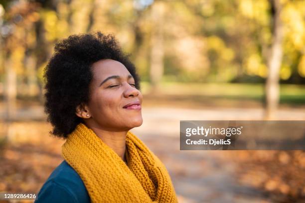 día de la mujer afroamericana soñando en el parque público en el hermoso día de otoño. - woman day dreaming fotografías e imágenes de stock