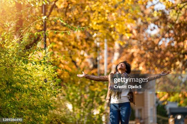 african american woman day dreaming in public park on beautiful autumn day. - gratitude stock pictures, royalty-free photos & images