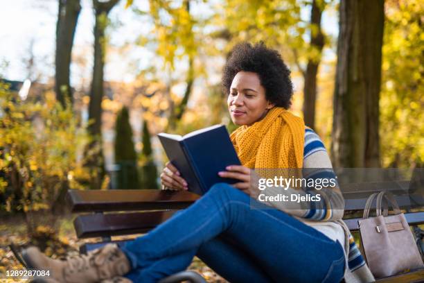 young african american woman reading a book in the public park. - person of color stock pictures, royalty-free photos & images