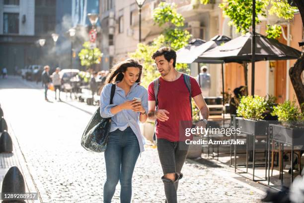 male and female tourists checking smart phone for directions - couple close up street stock pictures, royalty-free photos & images