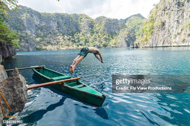 junger erwachsener mann taucht von boot, während auf den philippinen reisen - philippinen strand stock-fotos und bilder