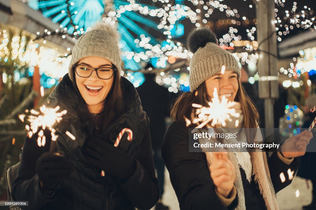 Two funny Girls holding burning sparkler during Christmas