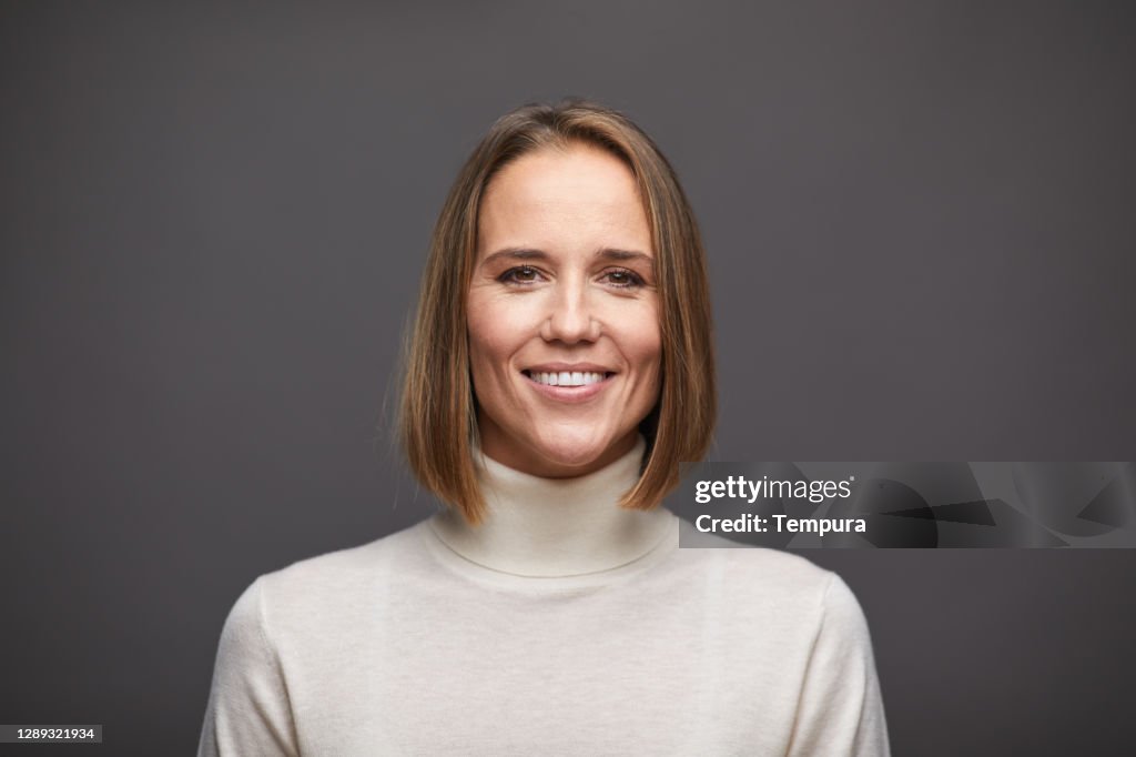 One woman looking at the camera and wearing a turtleneck sweater.