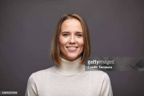 one woman looking at the camera and wearing a turtleneck sweater. - headshot gray background stock pictures, royalty-free photos & images