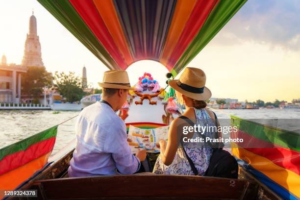 attractive mixed race romantic couple sightseeing wat arun in chao phraya river with longtail boat tour along the river in bangkok, thailand - bangkok boat stock pictures, royalty-free photos & images