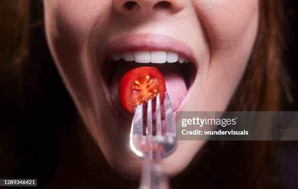 giovane donna bocca mangiare pomodoro ciliegino - mordere foto e immagini stock