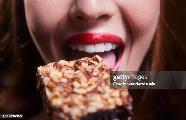 チョコレートブラウニーを食べる若い女性の口 - チョコレートケーキ ストックフォトと画像
