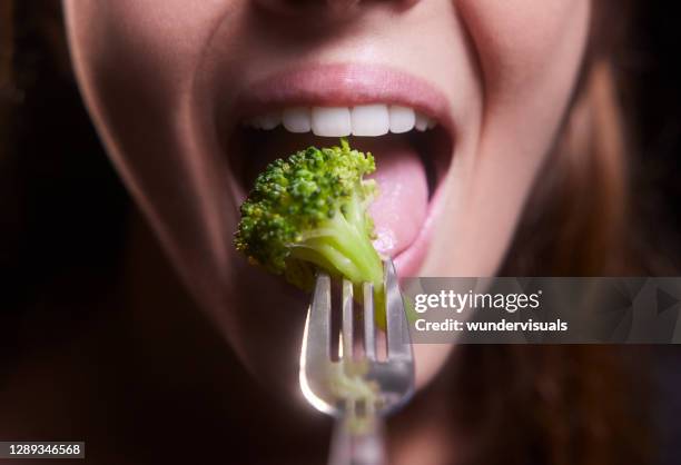 young woman mouth eating broccoli - juicy lips stock pictures, royalty-free photos & images