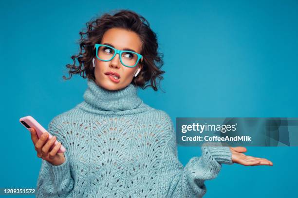 belle femme bouleversée restant devant le fond bleu avec le téléphone intelligent - problem photos et images de collection