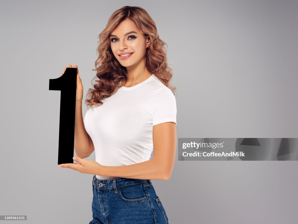 Chica linda sostiene sosteniendo artificial número uno