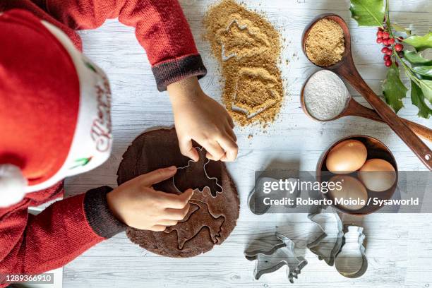 cute child with santa hat using the cookie cutter at christmas - biscuit dough stock pictures, royalty-free photos & images
