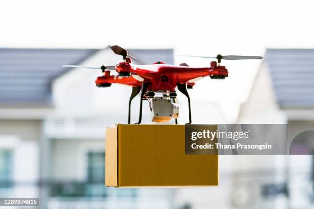 drone delivering package over cityscape - drone stockfoto's en -beelden