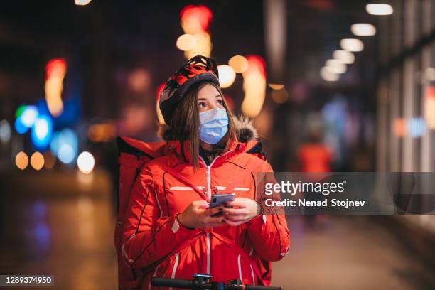 female delivery person using smartphone and looking for customer's address - night delivery stock pictures, royalty-free photos & images