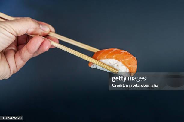close-up of chopsticks holding sushi - chopsticks stock-fotos und bilder