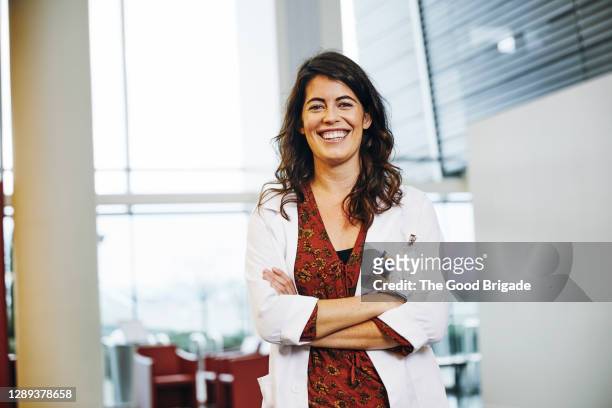 portrait of confident female doctor with arms crossed standing in hospital - doctor portrait stockfoto's en -beelden