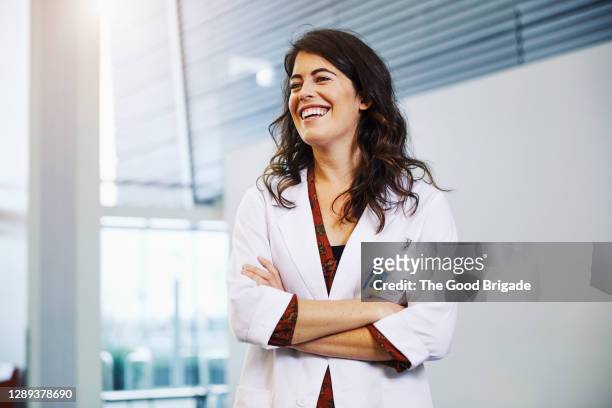 confident female doctor with arms crossed standing in hospital - healthcare and medicine stock-fotos und bilder