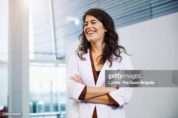 confident female doctor with arms crossed standing in hospital - authenticity foto e immagini stock