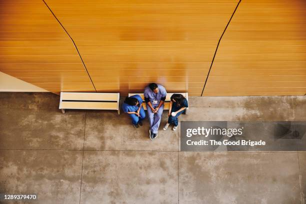 directly above shot of male and female nurses sitting on bench in hospital - bench dedication stock pictures, royalty-free photos & images