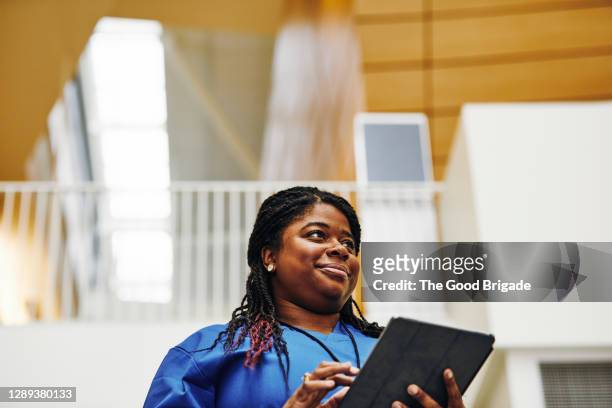 female nurse using digital tablet in hospital corridor - black woman nurse bildbanksfoton och bilder