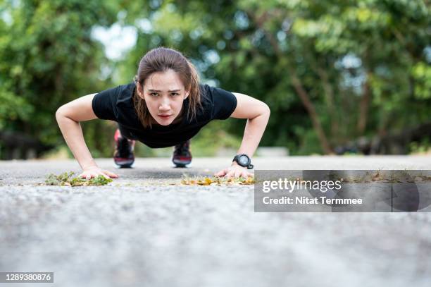 asian young woman exercising outdoors. sporty women doing pushing-ups workout on the bridge at urban park outdoors. - body building stock pictures, royalty-free photos & images