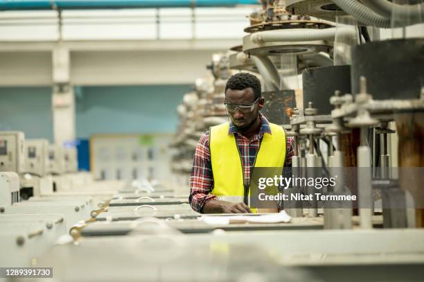 african male plastic worker examining automated machinery production line at factory. - manga dobrada - fotografias e filmes do acervo