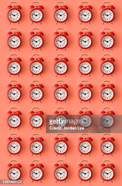 red alarm clock on orange colour background - clock pattern photos et images de collection