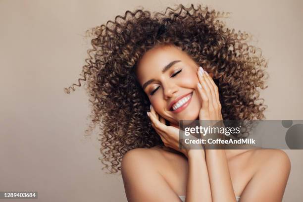 verticale de studio de jeune femme attirante avec la coiffure bouclée volumineuse volumineuse - woman hand face photos et images de collection