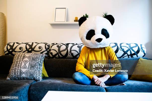 relaxed woman in panda mask sitting on sofa at home - funny mask 個照片及圖片檔