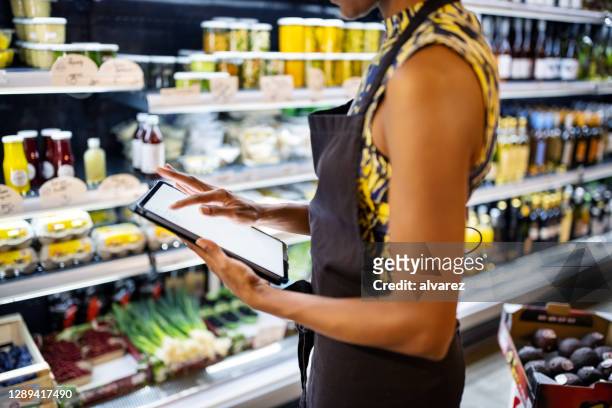 sales clerk checking inventory in delicatessen - groceries tablet stock pictures, royalty-free photos & images