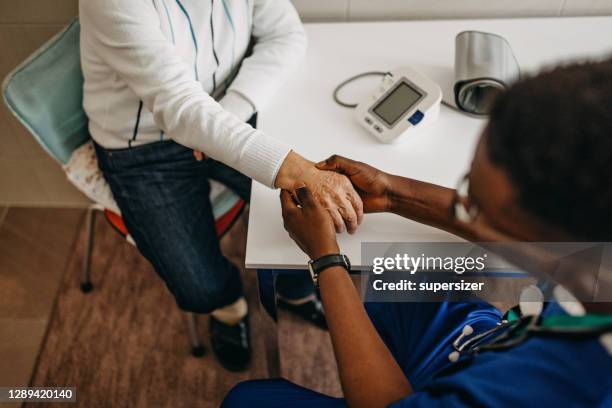 senior man treated by young doctor at home - arthritic hands stock pictures, royalty-free photos & images