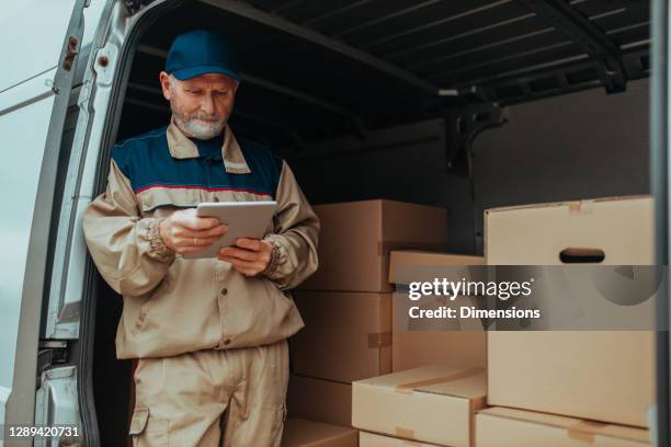 delivery man using digital tablet and checking order list - moving service imagens e fotografias de stock