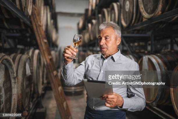 senior sommelier testen gealterten whisky in alten keller. - whisky distillery stock-fotos und bilder